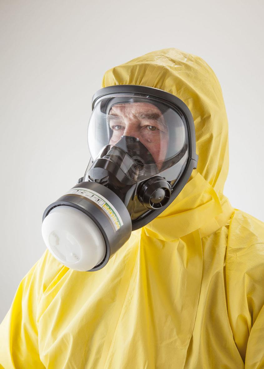 Person i gul skyddsoverall och gasmask