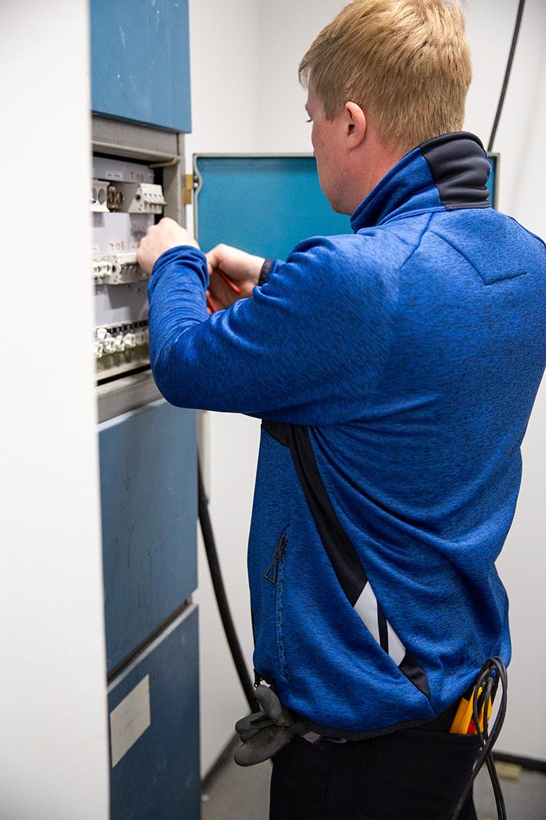 Man i blå fleecetröja arbetar med elcentral