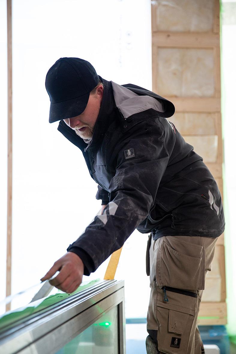 Man i svart jacka och svart keps arbetar med ett transparent skärmar eller display