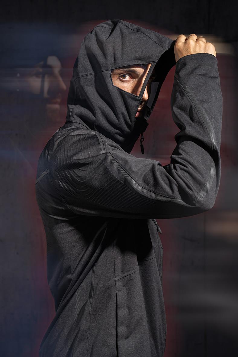 Person i svart vinterjacka med huva och ansiktsmask, ser ut att vara redo för kallt väder