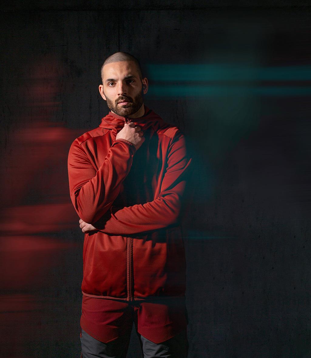 Man i röd fleecejacka med huva står mot mörk bakgrund