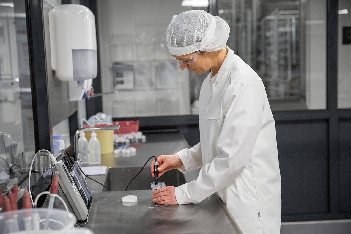 Forskare i labbkläder och skyddshatt arbetar med utrustning i ett laboratorium