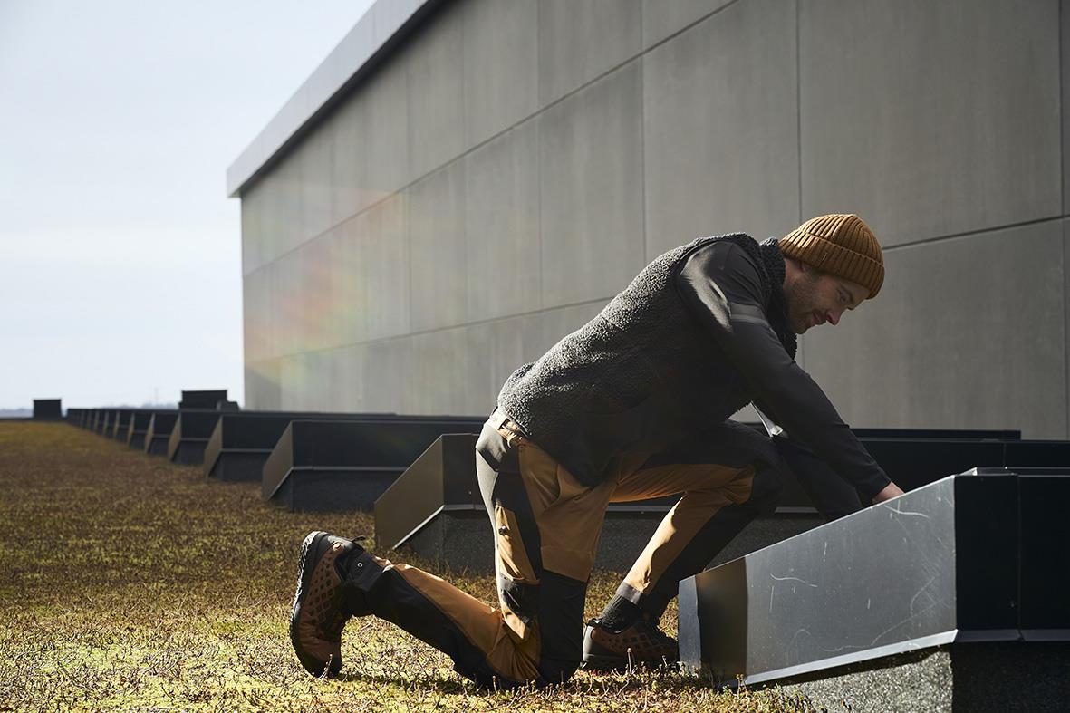 Person i fiberpälsväst och mössa som undersöker en metalllåda utomhus