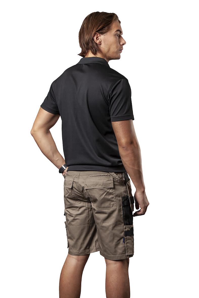 Man i svart funktionspiké och beige arbetsbyxor, sett bakifrån