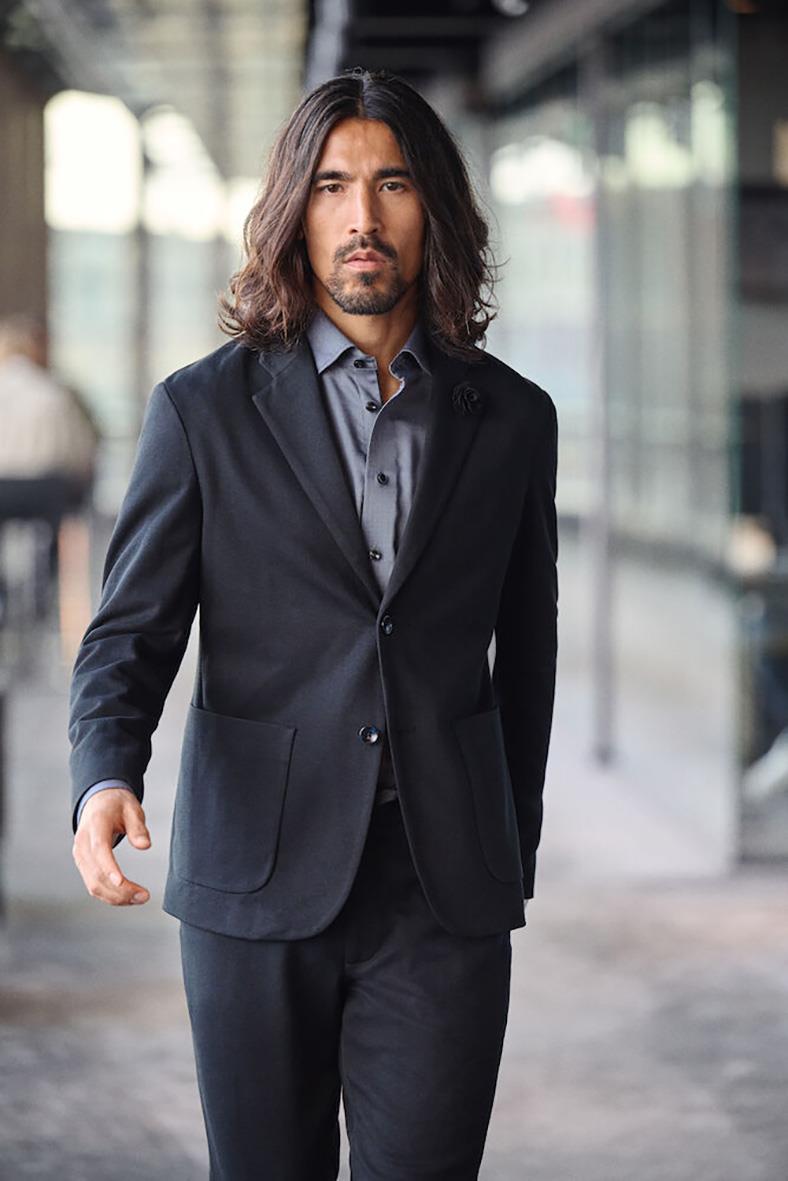 Man i marinblå casual blazer och skjorta går i en modern stadsmiljö