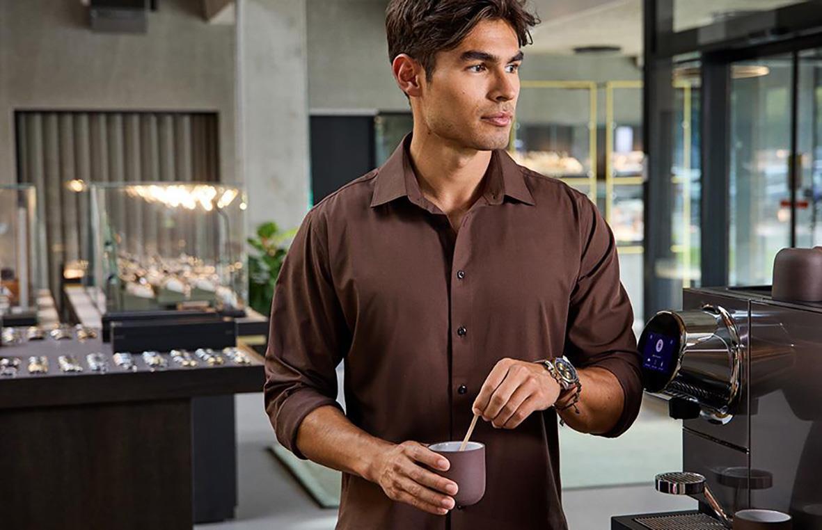 Man i brunt skjorta som dricker kaffe i ett modernt kafé