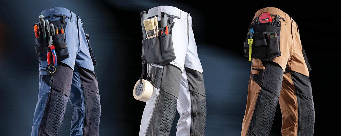 Tre hantverkarbyxor i mörk marin med hängfickor och verktyg, visade i olika färger