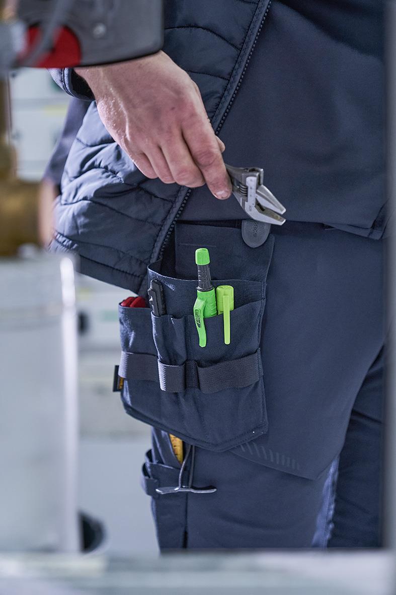 Elektriker med mörk marin hängficka med verktyg och tång i fickan