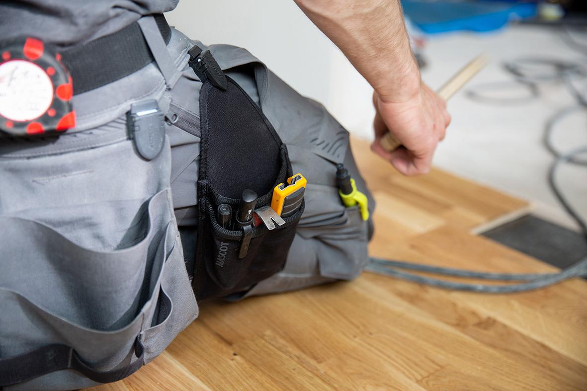 Svart hängficka med verktyg och verktygsbälte på en hantverkare