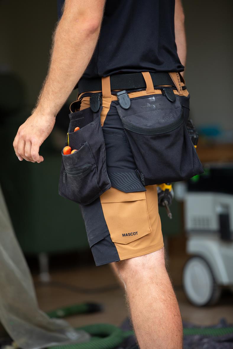 Svart hängficka med flera fack och verktygsfästen, bärs av person i shorts