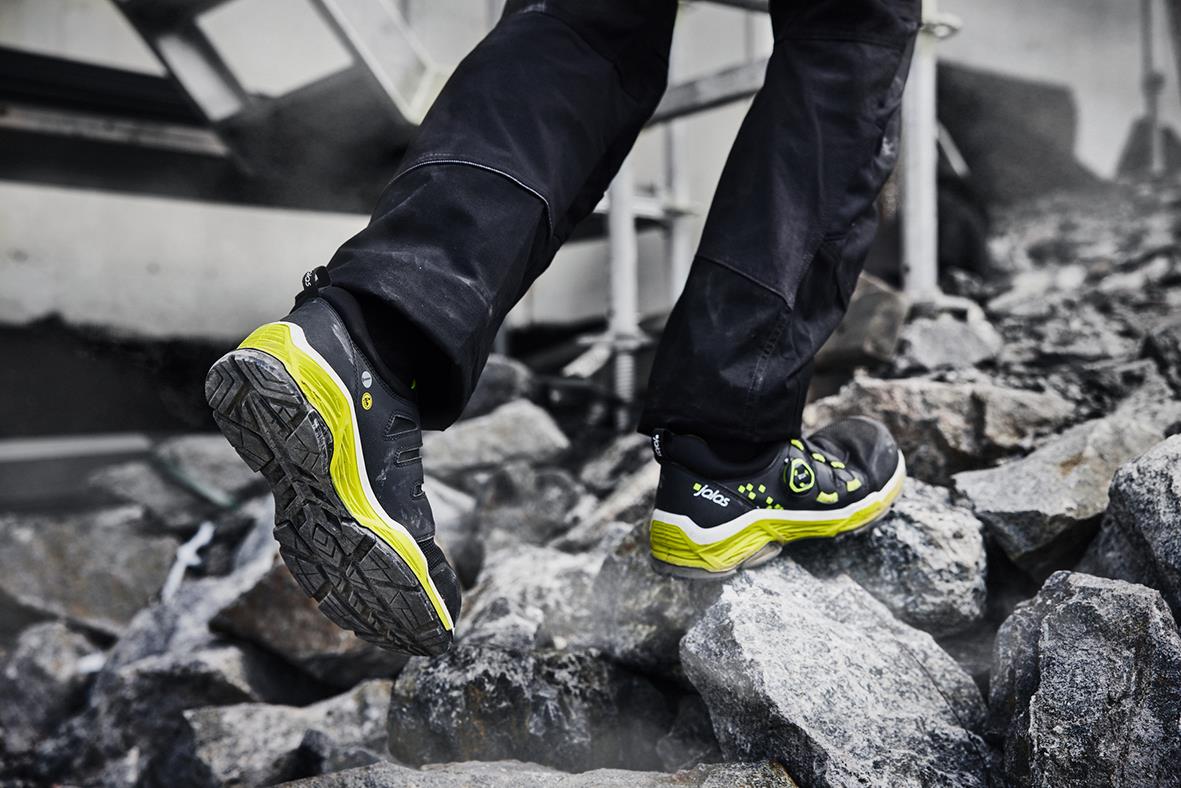 Person som går på sten med svarta och gula skyddsskor Jalas TIO 2068