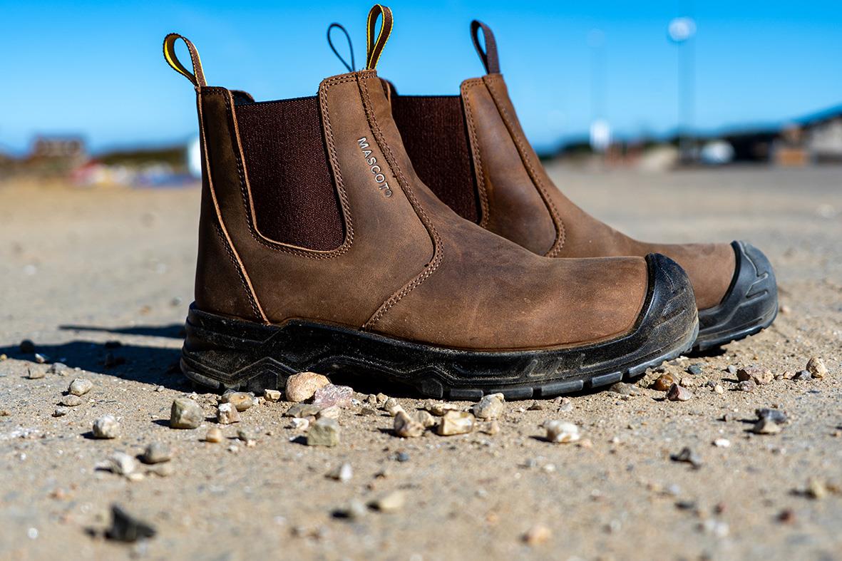 Skyddskänga Mascot F1000-715 S3S i nötbrun/svart, storlek 35, på grusig mark