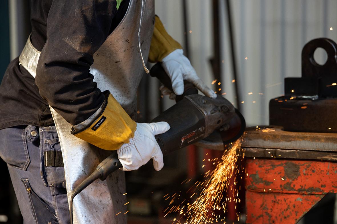 Person som svetsar med skyddshandskar i en industriell miljö