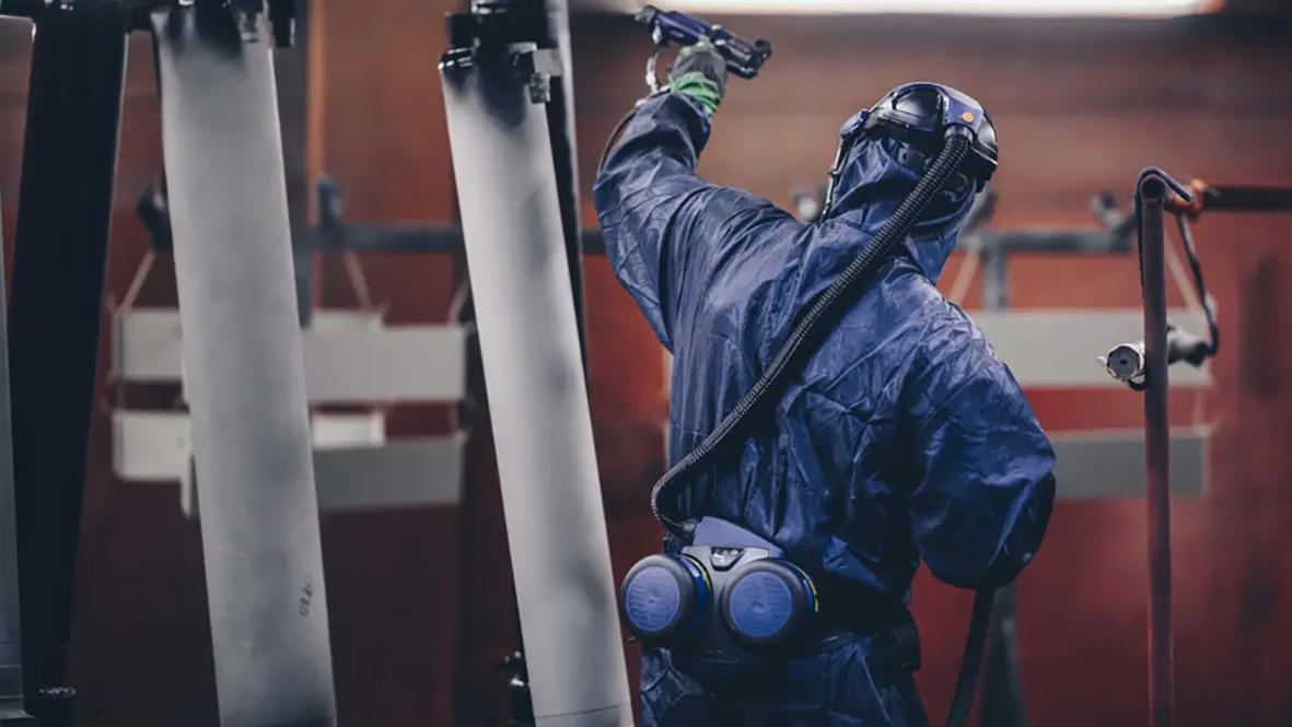 Person i skyddsutrustning arbetar med fläktpaket Sundström SR 500/570 i industriell miljö