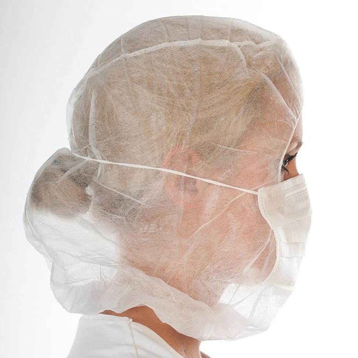 Kvinna i vit munskydd och skyddshuv med hårnät, profilvy