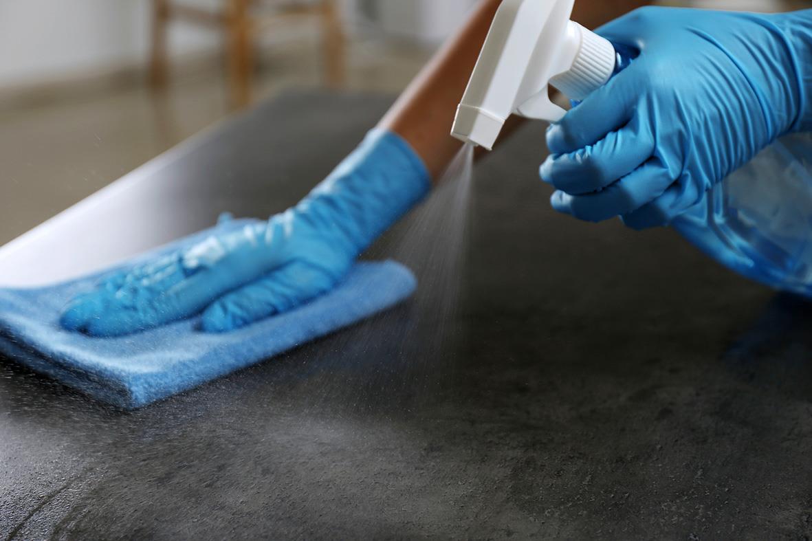 Person som rengör en yta med blå nitrilhandske på handen