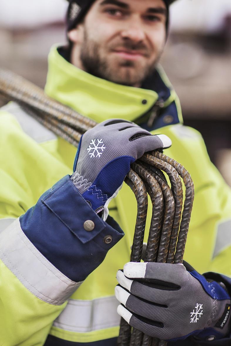 Man i vinterhandske Tegera 295 vattentät, blå och grå, håller i armeringsjärn