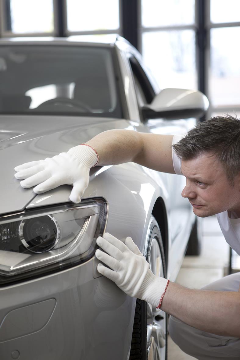 Person som inspekterar en silverbil med vita bomull/nylon Tegera 310A handskar i ett inomhusgarage