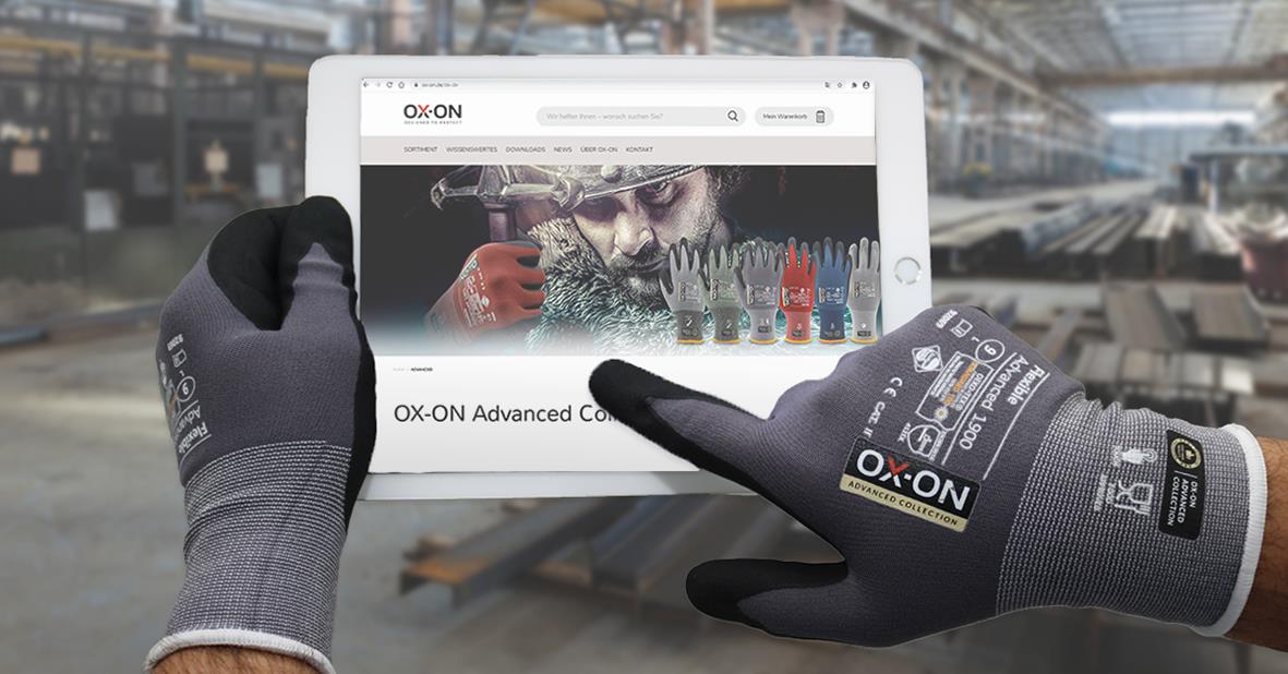 Person håller i en surfplatta med arbetshandske i industriell miljö