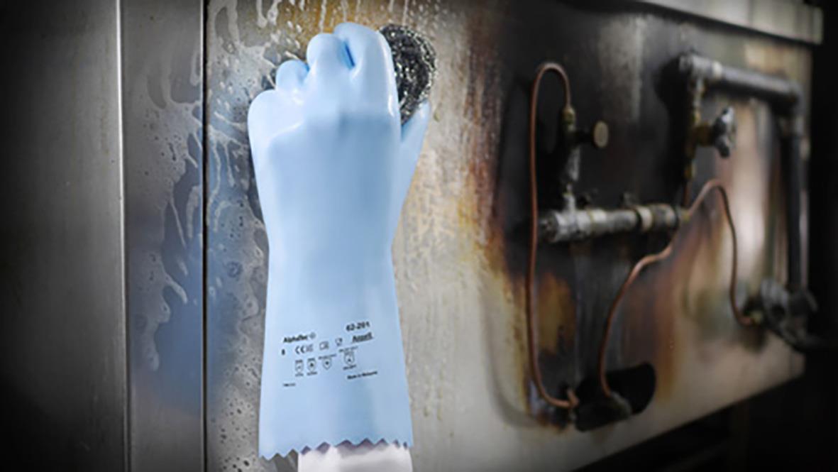 Hand i en kemskyddshandske AlphaTec 62-401 som rengörs mot en metallvägg