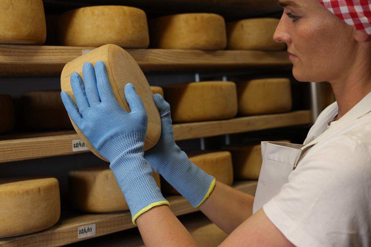 Person som hanterar ost med skärskyddshandske Tegera 913 Blå 8 i ett ostlager