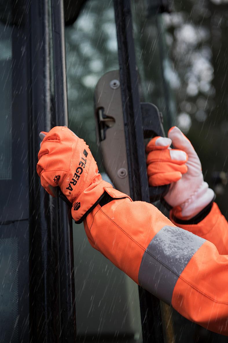Vinterhandske Tegera 288 i orange på en person som öppnar en dörr i regn