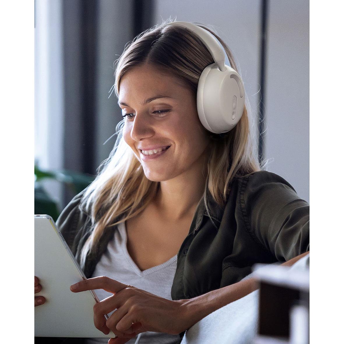 Kvinna med vita trådlösa hörlurar som använder en surfplatta i ett inomhusmiljö