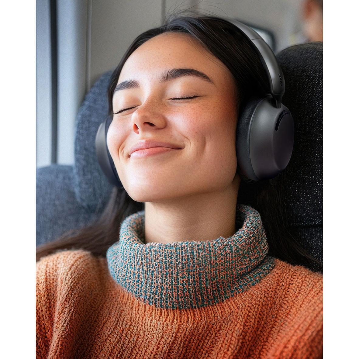 Kvinna med stängda ögon bär trådlösa over-ear hörlurar i svart och njuter av ljud