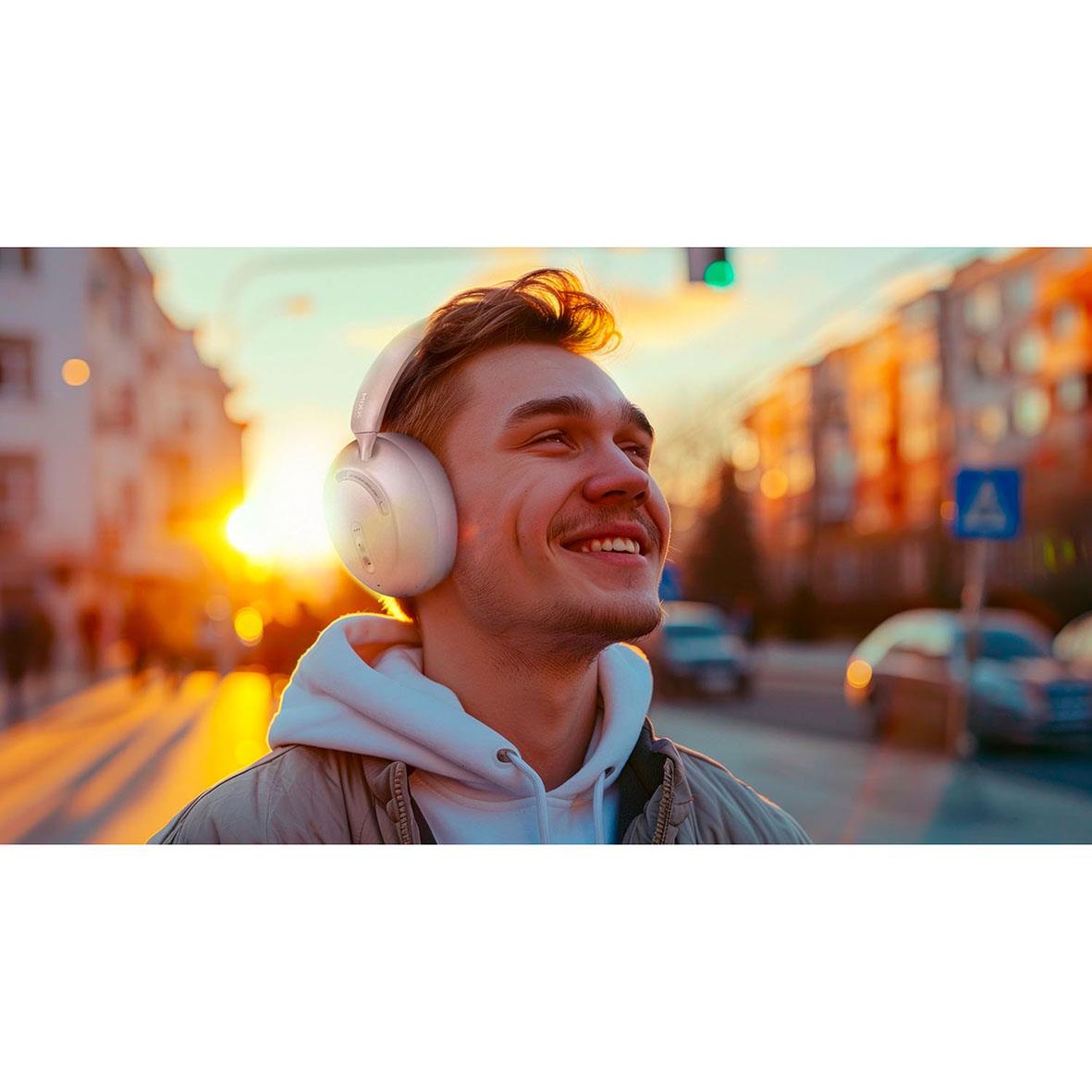 Ung man med Mixx Over-Ear trådlösa hörlurar med ANC i stadsmiljö vid solnedgång