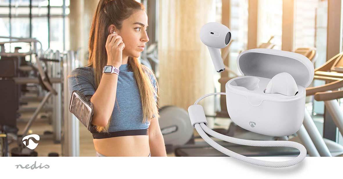 Kvinna i gym med vita trådlösa in-ear hörlurar Nedis