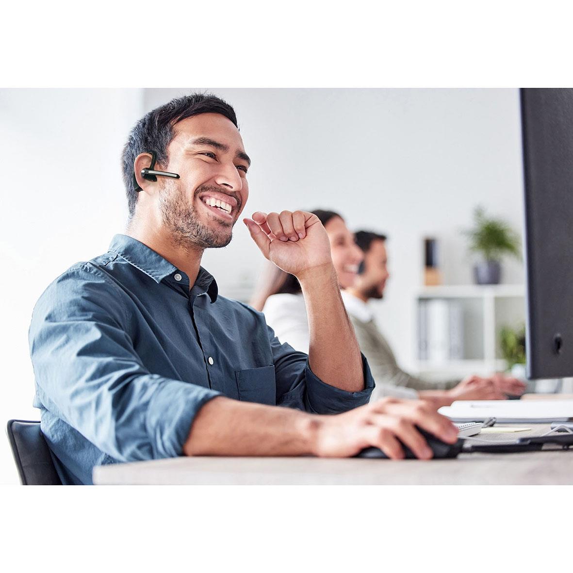 Man med headset och mikrofon arbetar vid dator i kontorsmiljö