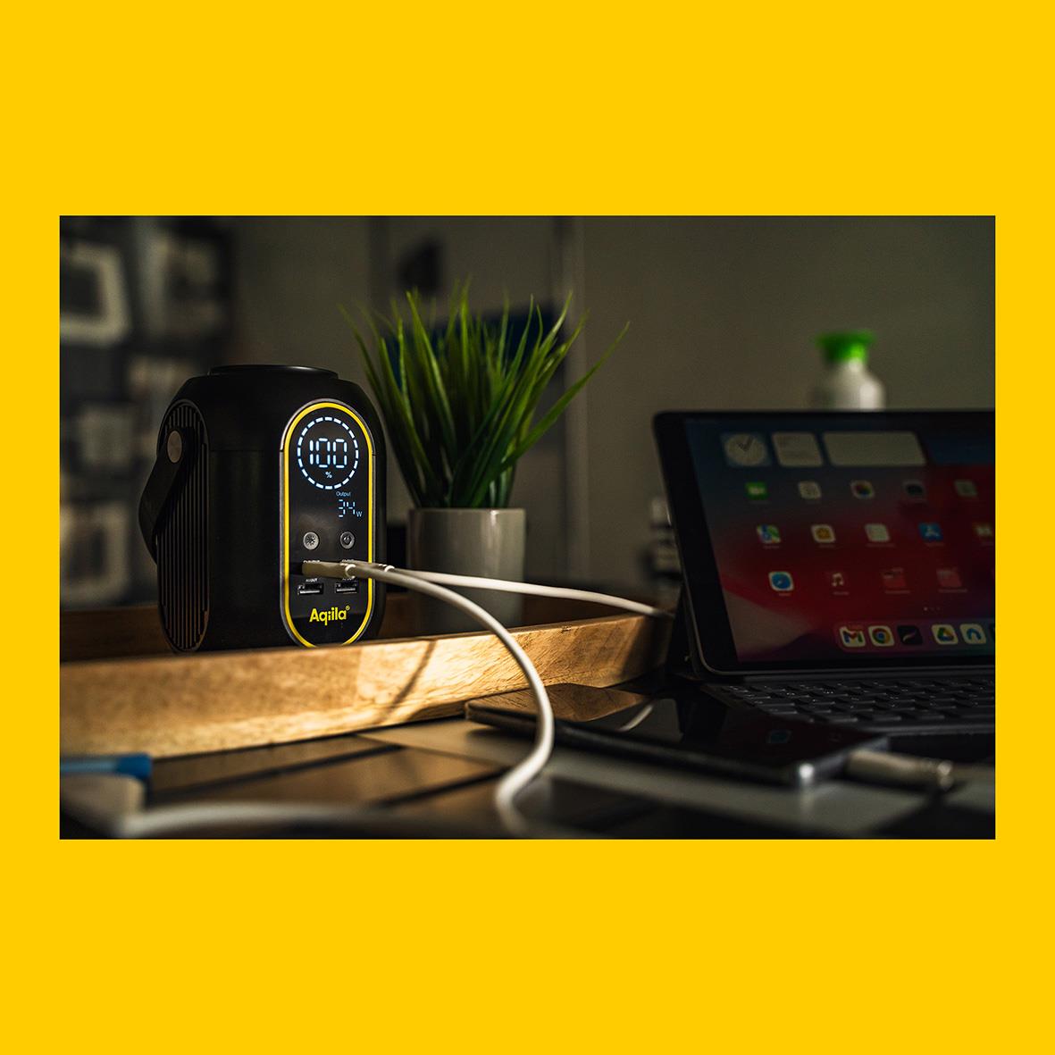 Powerstation Aqiila Powerbird S140 med 54000 mAh och 200Wh laddar en enhet framför en laptop på ett bord