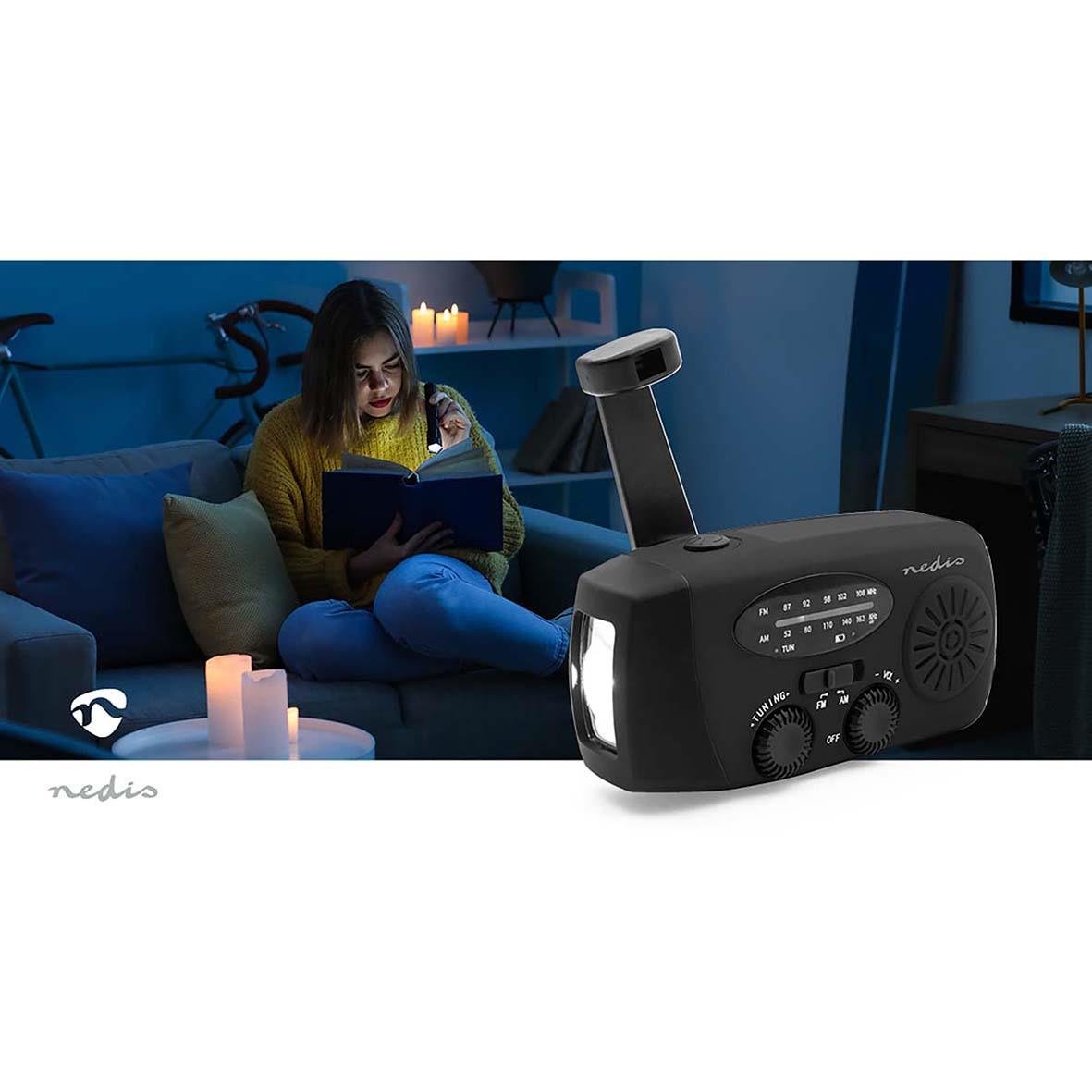 Nedis portabel DAB/FM nödradio i svart på ett bord med en kvinna som läser en bok i bakgrunden