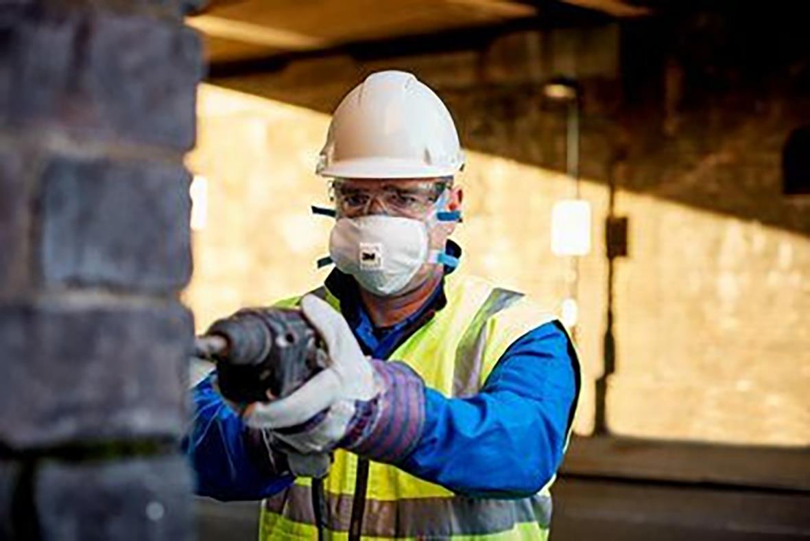 Person i skyddsutrustning använder halvmask 3M 8825+ FFP2 R D V med ventil i industriell miljö