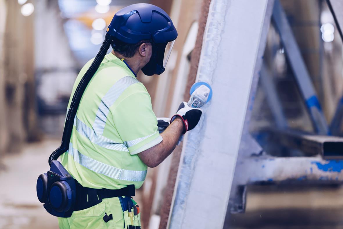Arbetare i byggmiljö med skyddshjälm och reflexväst som inspekterar ett ventilationssystem