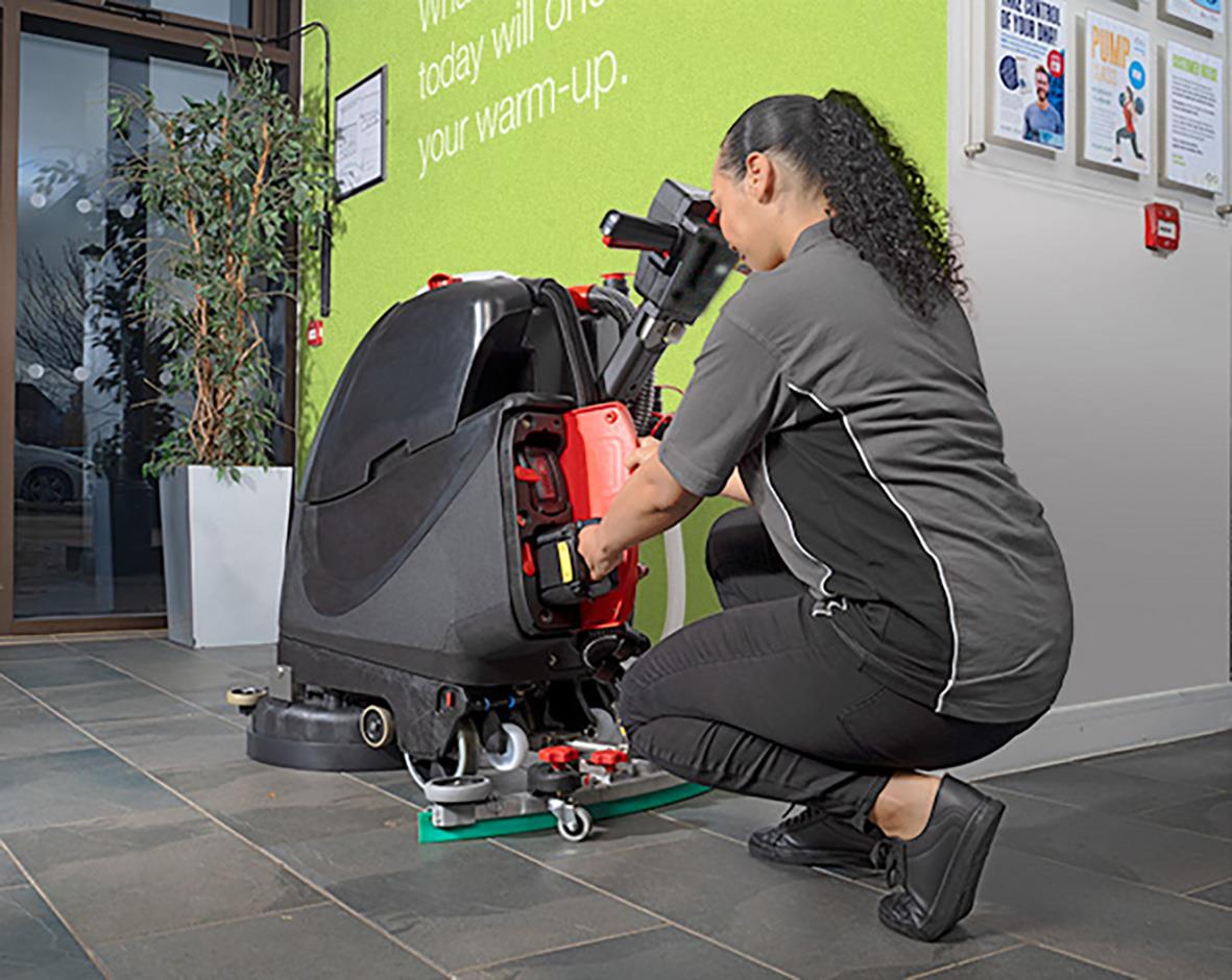 Kvinna som justerar en kombiskurmaskin Numatic TTB3045NXUB 450mm exkl batteri på golvet inomhus