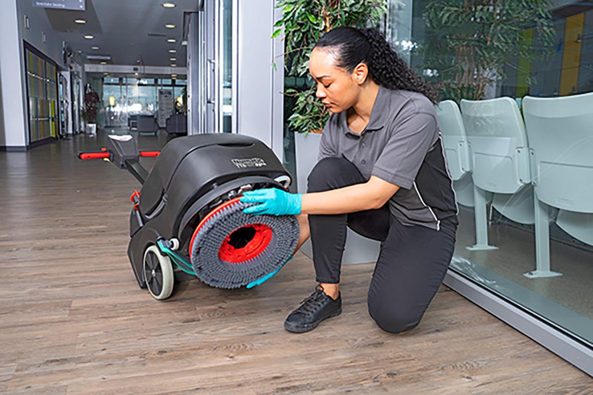 Kvinna rengör kombiskurmaskin Numatic TTB1840NXUB på golv inomhus