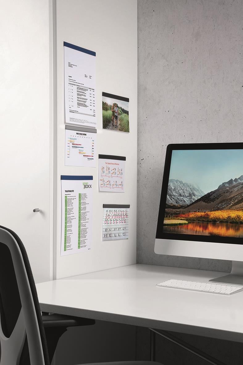 Vägg med olika dokument och bilder bredvid en dator på ett skrivbord