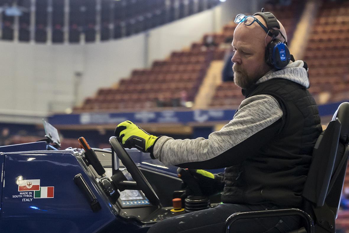 Man med vinterhandske som kör fordon i inomhusarena